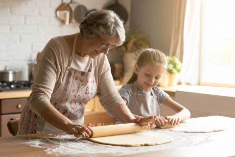 Warm, inviting kitchen scene with an elderly grandmother and her granddaughter baking